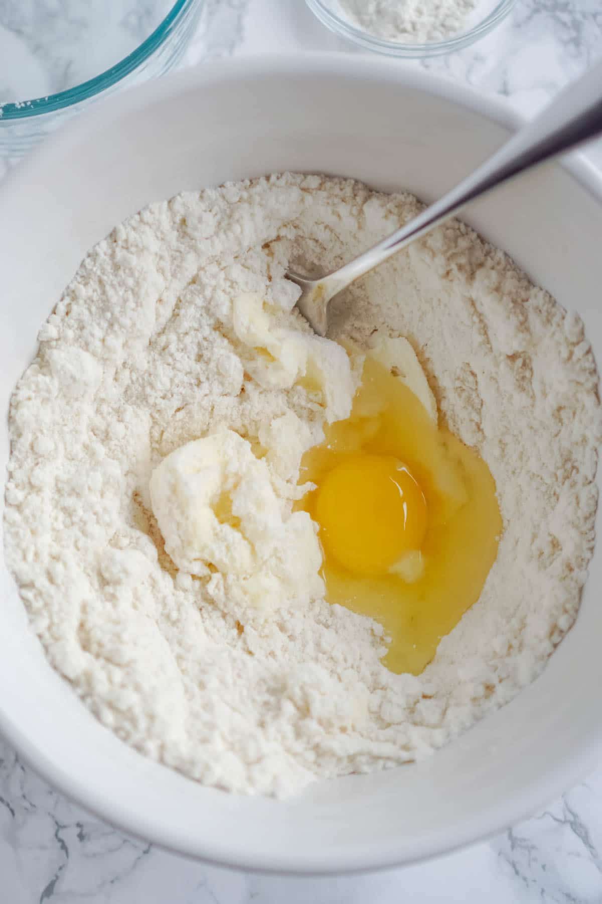Hvid skål med sukkerkageblanding og et æg i den