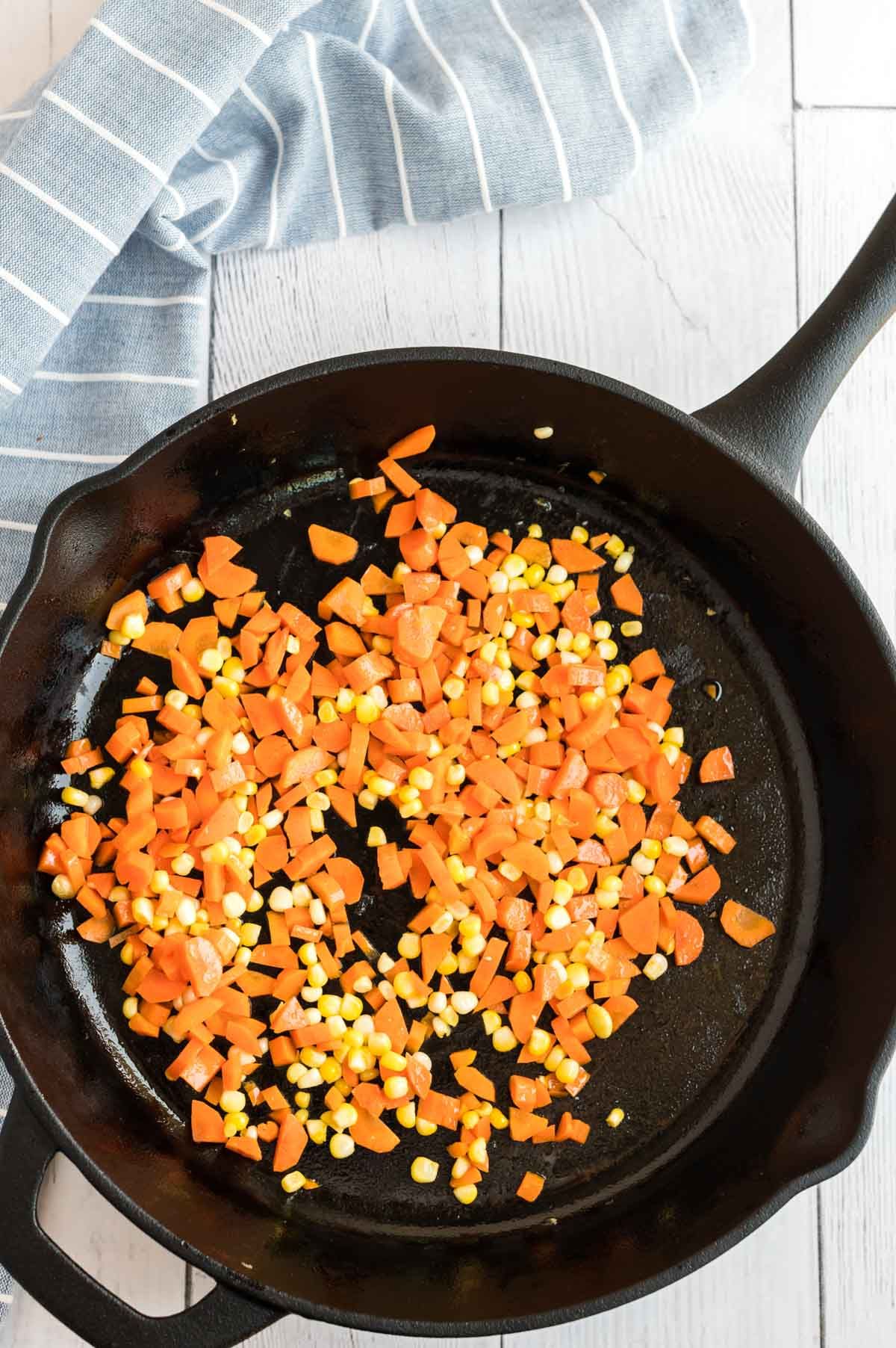 Nakrájanú mrkvu a kukuricu na liatinovej panvici