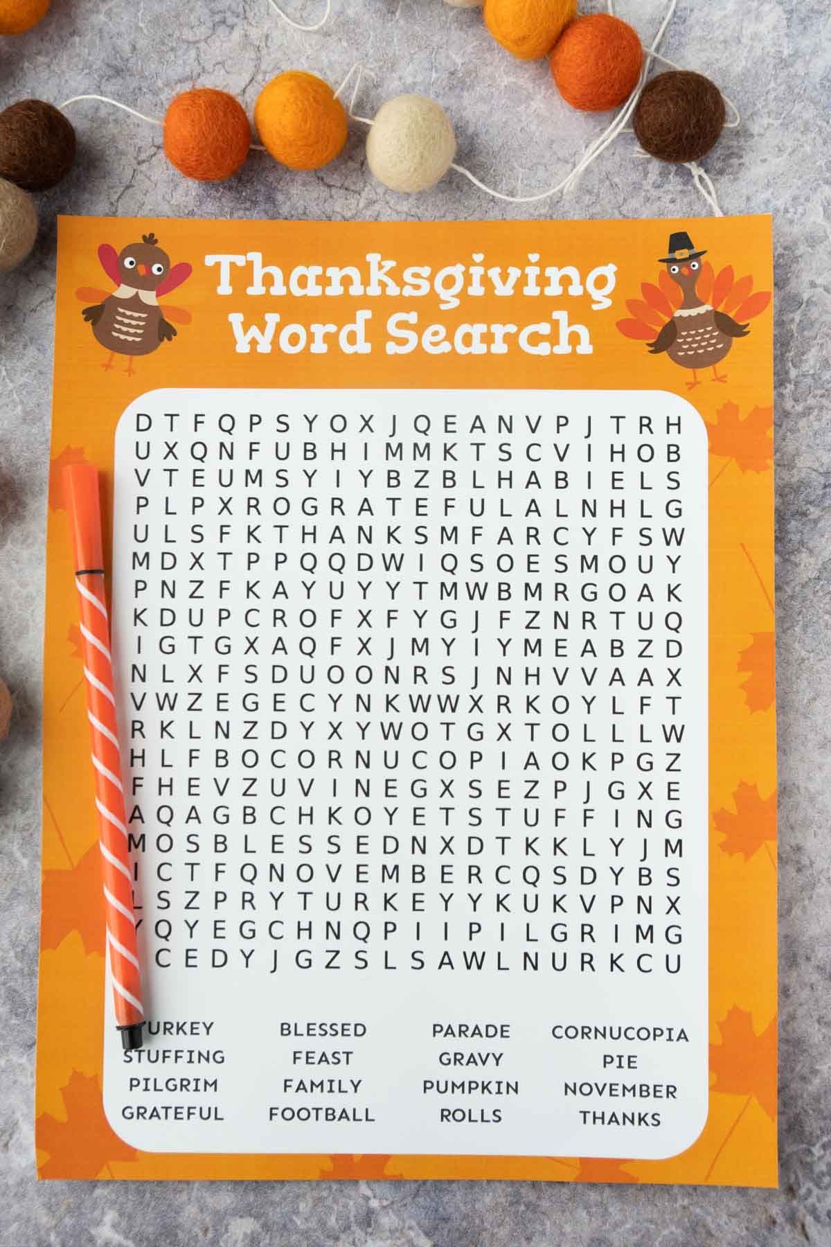 Utskrift av Thanksgiving-ordsökning med en penna och filtbollkrans