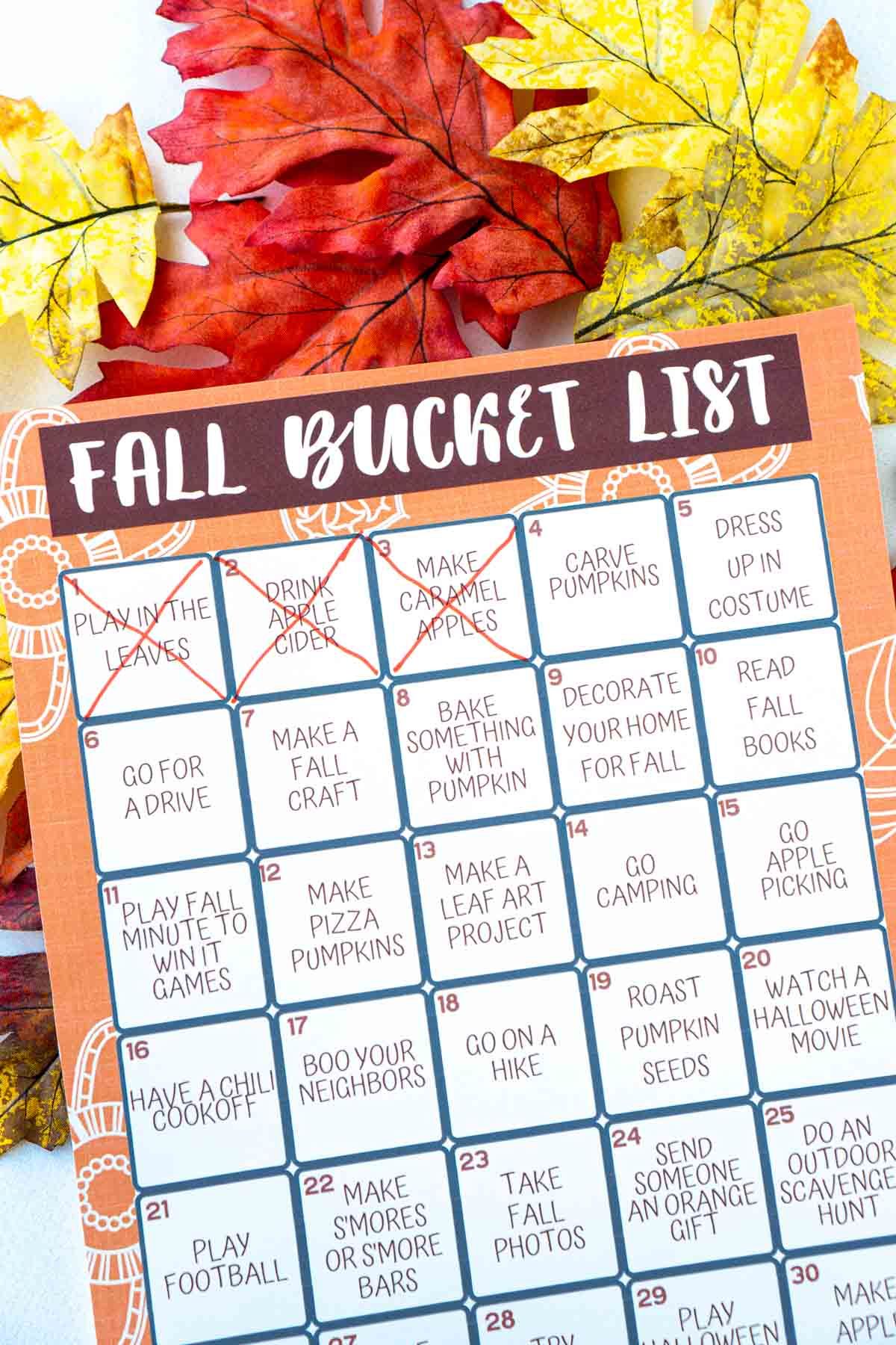 Een herfst-bucketlist met drie items gemarkeerd bovenop nepblaadjes