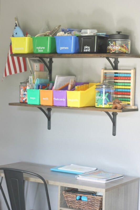 Un estante con baldes de almacenamiento de colores, etiquetas y material escolar personalizado