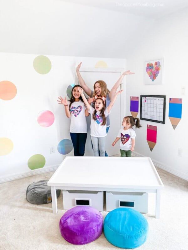 Meitenes istabā ar polka punktiem uz sienas un pupiņu maisu krēsliem un baltu galdu