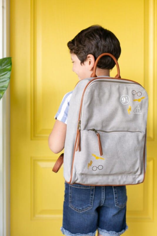 Chlapec stojící před žlutými dveřmi s batohem Harryho Pottera
