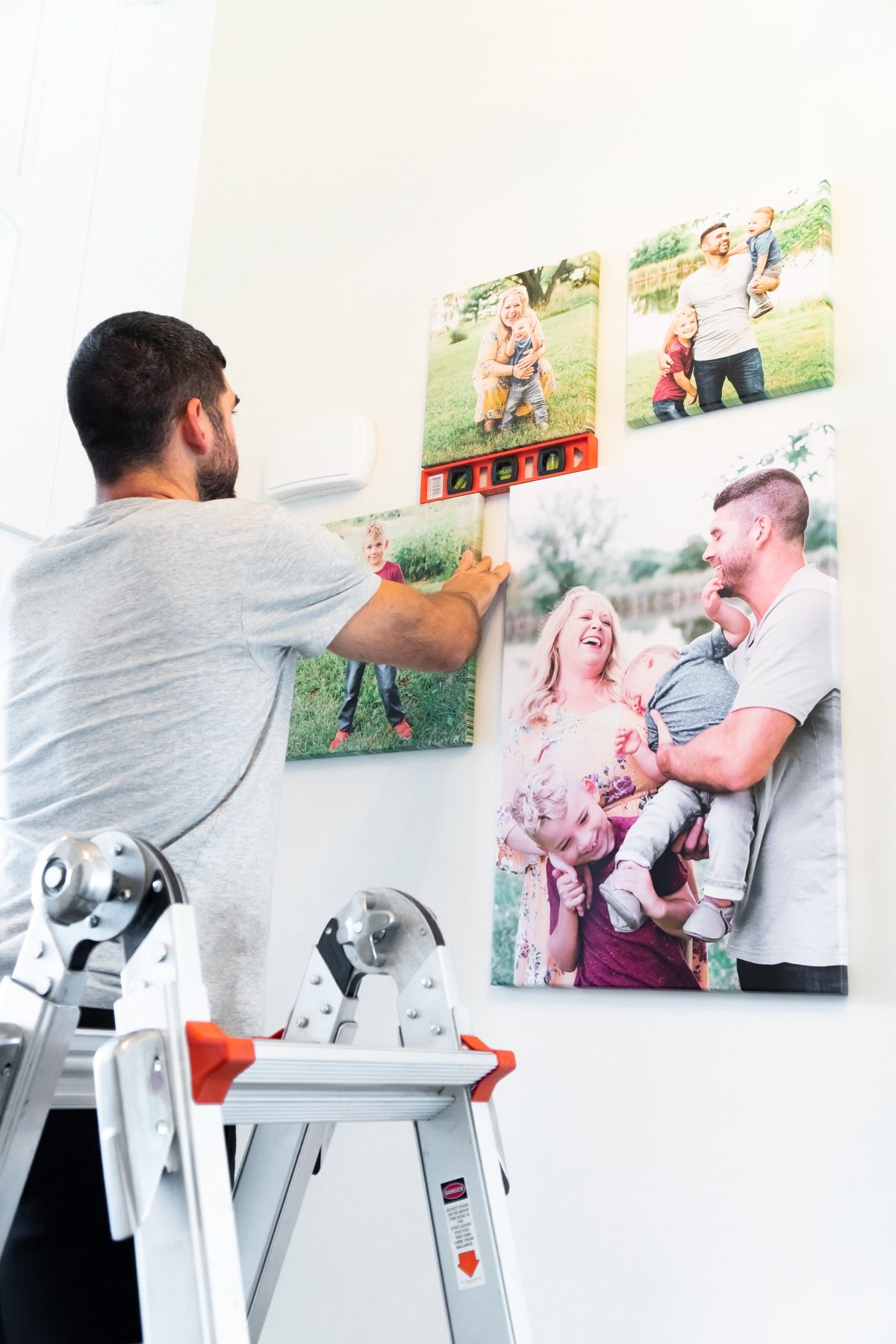 Človek na lestvi doda platna na DIY foto steno