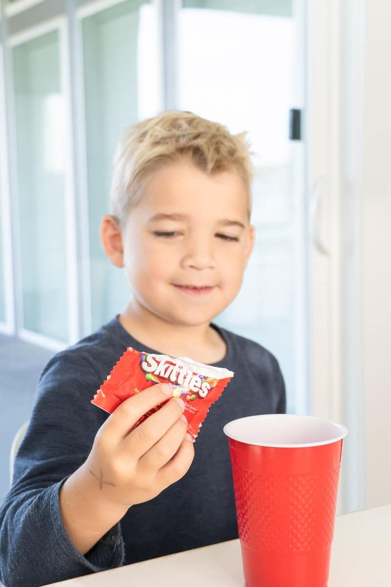 Abocar Skittles en una tassa per a un joc de Gratitude Skittles