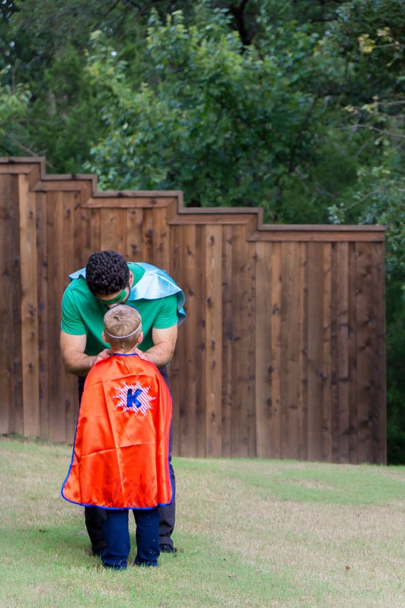 Pai ajudando filho a vestir uma fantasia de super-herói faça você mesmo