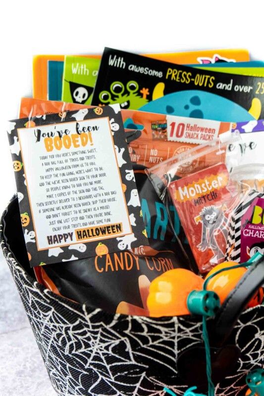 Košík s pavučinami naplněný halloweenskými knihami, hrami a vy