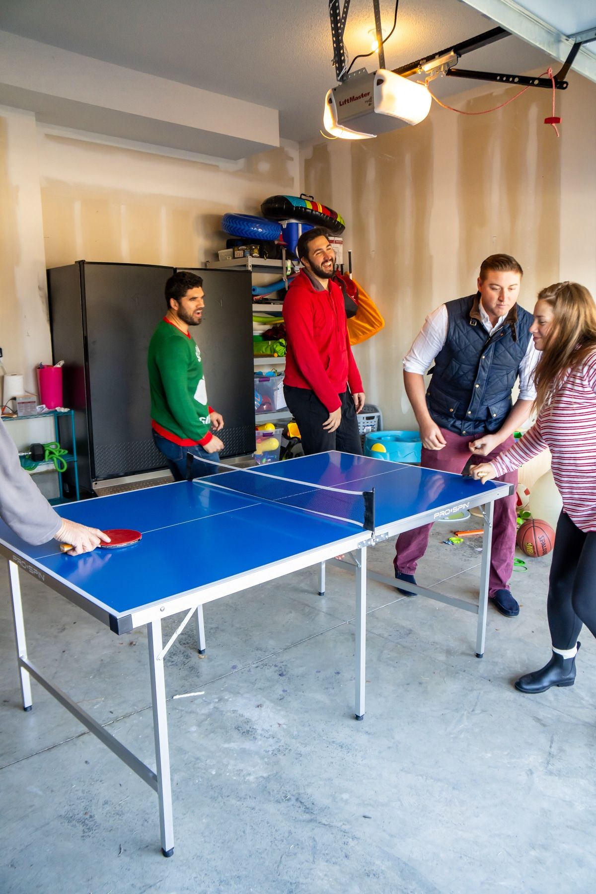 Familia jugando juegos de ping pong alrededor de una mesa de ping pong