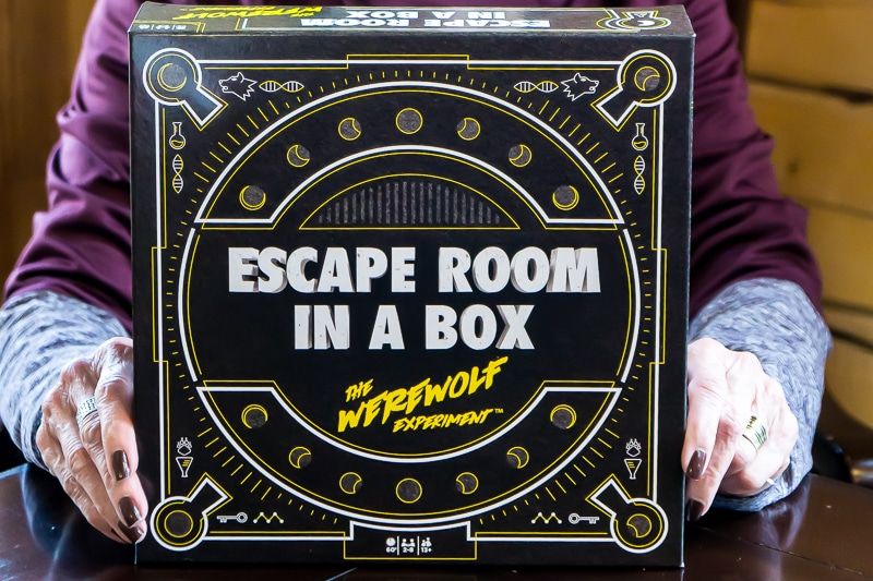 Una mujer sosteniendo Escape Room in a Box Game