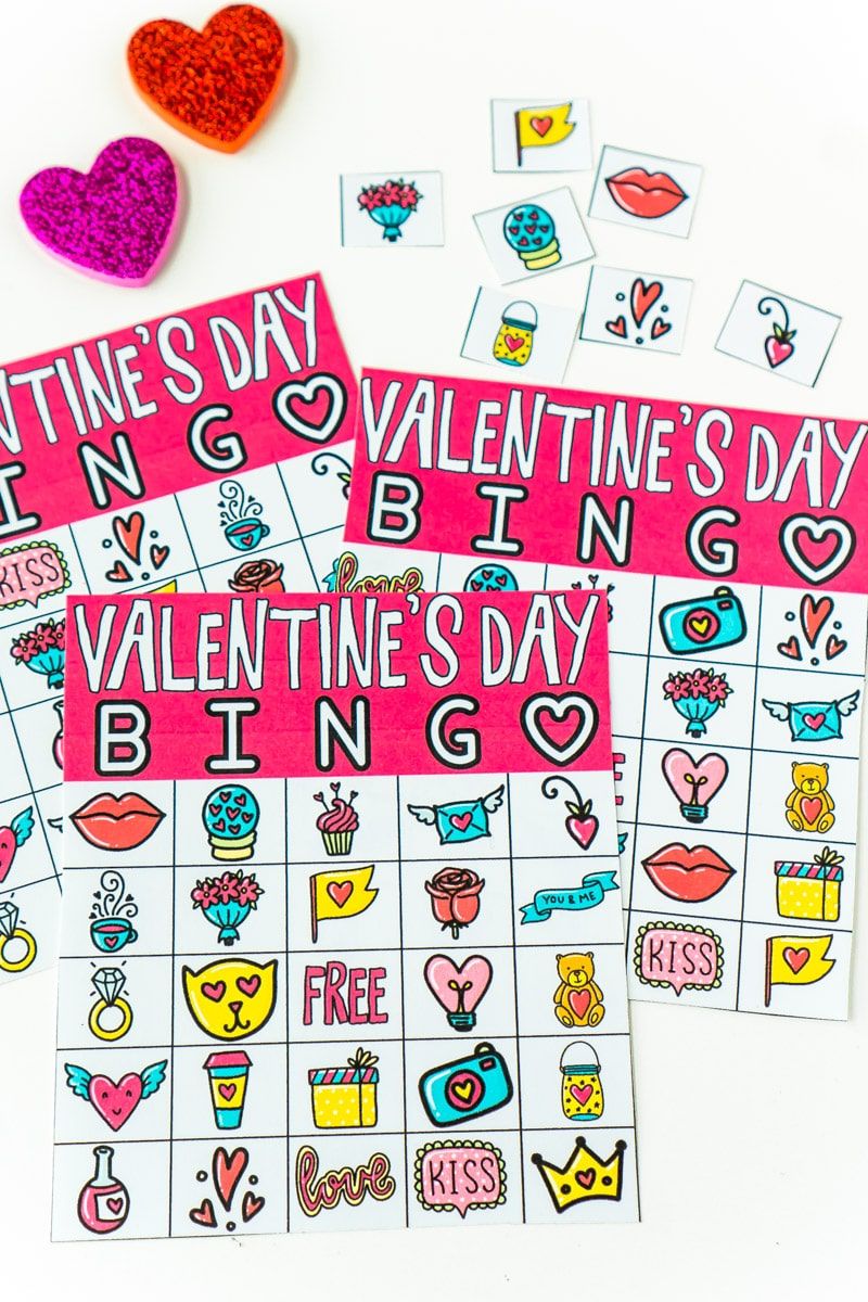 Tres cartones de bingo de San Valentín con marcadores y maestros que llaman