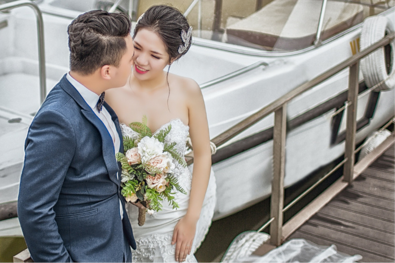   Νεοπαντρεμένο ζευγάρι που στέκεται στην καφέ ξύλινη αποβάθρα κοντά σε βάρκα