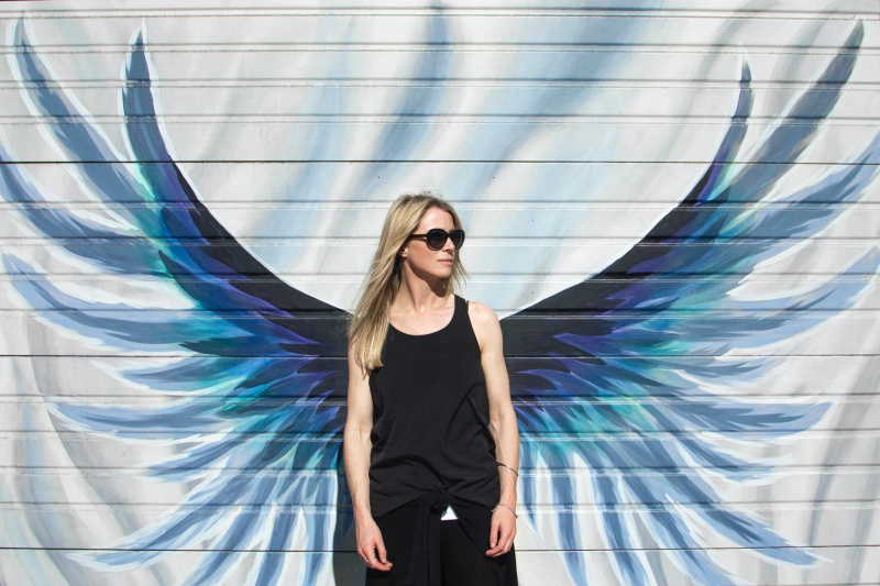  Жена в черна дреха, стояща със сини ангелски крила
