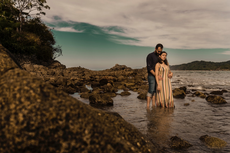   Momentos doces de um casal romântico em pé na praia rochosa