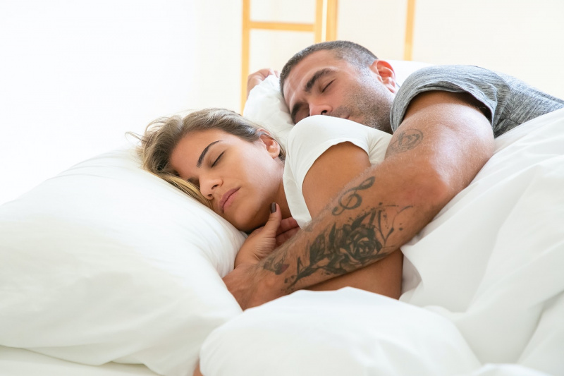   Muž objímá ženu, zatímco spí