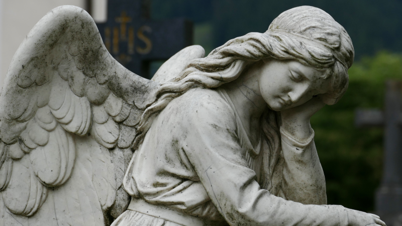   Una estatua de ángel con la mano derecha en la cara.