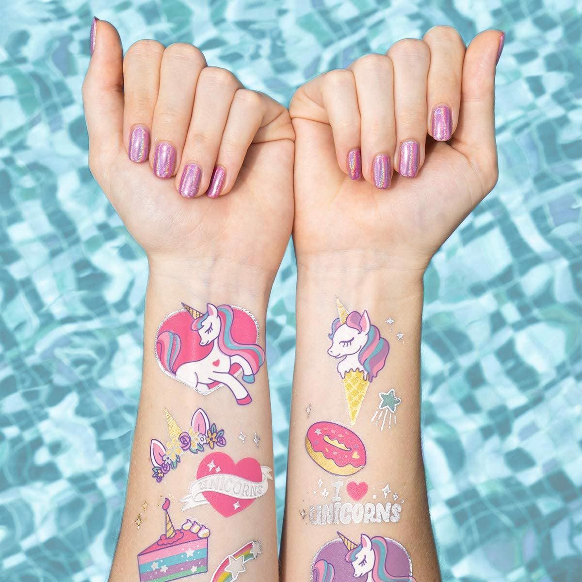 Brazos de niñas con tatuajes de unicornio sobre una piscina