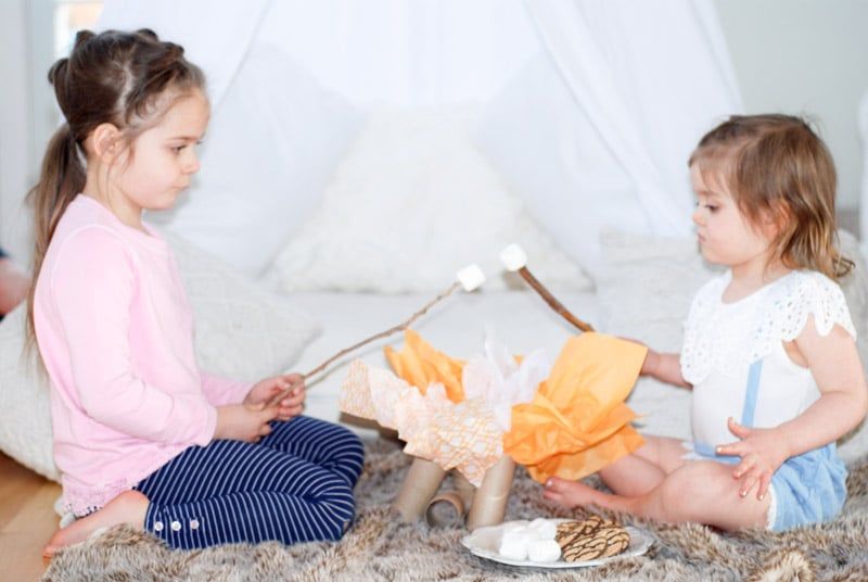 Crianças acampando dentro de casa e assando marshmallows