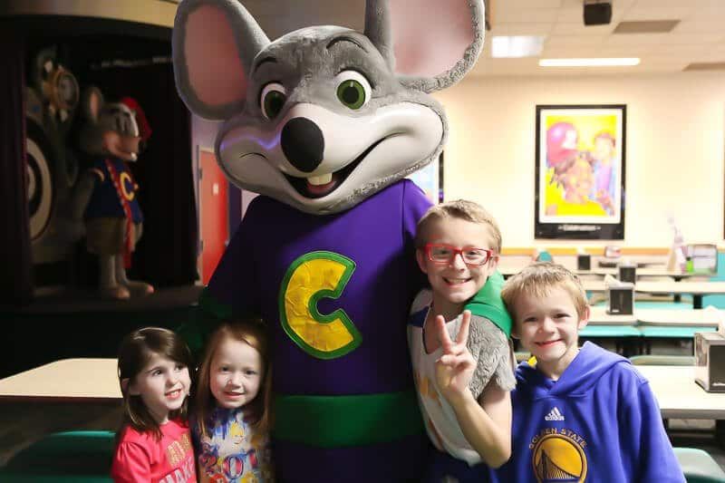 Kinderen poseren met Chuck E Cheese op een verjaardagsfeestje van Chuck E Cheese