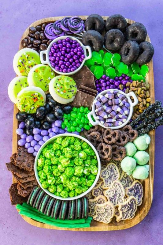 Rechteckiges Holztablett mit lila, schwarzen und grünen Snacks