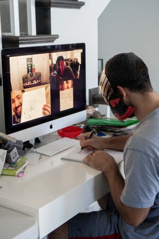 Mann, der ein Bild vor einem Computer mit Leuten auf Zoom zeichnet