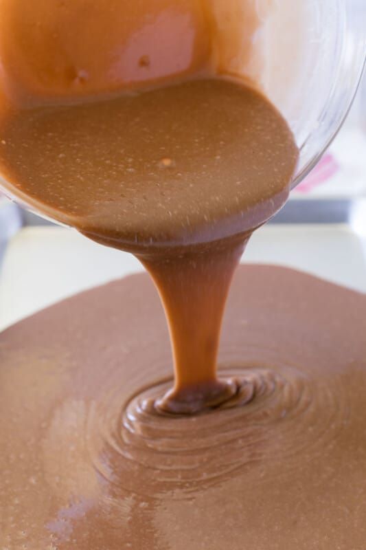 קערת זכוכית שופכת חומר לעוגת בראוניז שוקולד לתבנית