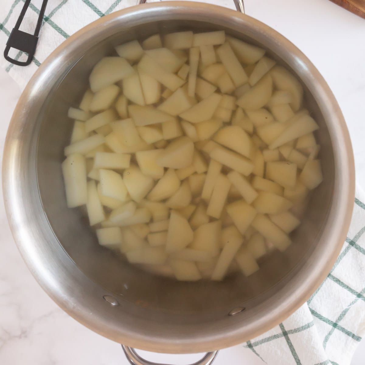Kovový hrnec s nakrájenými bramborami a vodou
