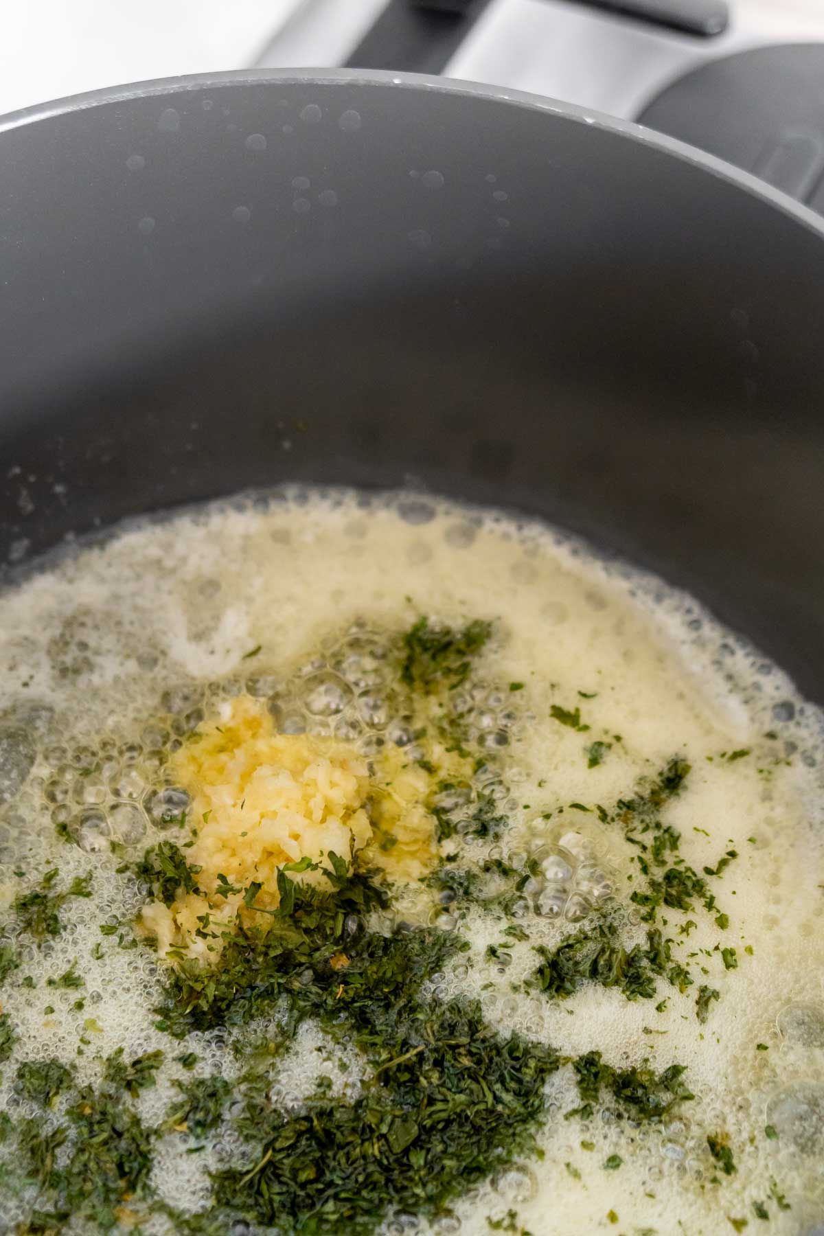 Mentega cair dengan bawang putih dan pasli dalam kuali