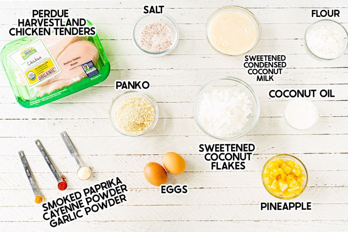 Ingredientes para licitaciones de pollo de coco sobre una placa de madera blanca