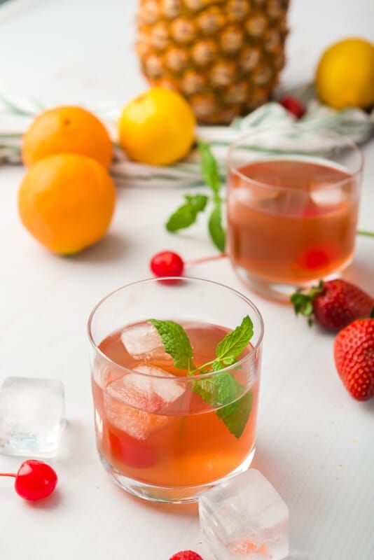 Δύο ποτήρια με γροθιά φρούτων και ένα μάτσο φρούτα γύρω στο τραπέζι