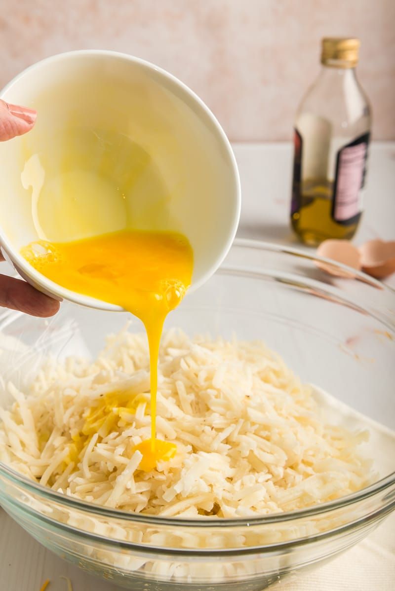 Женщина наливает яйцо в миску с картофельными оладьями