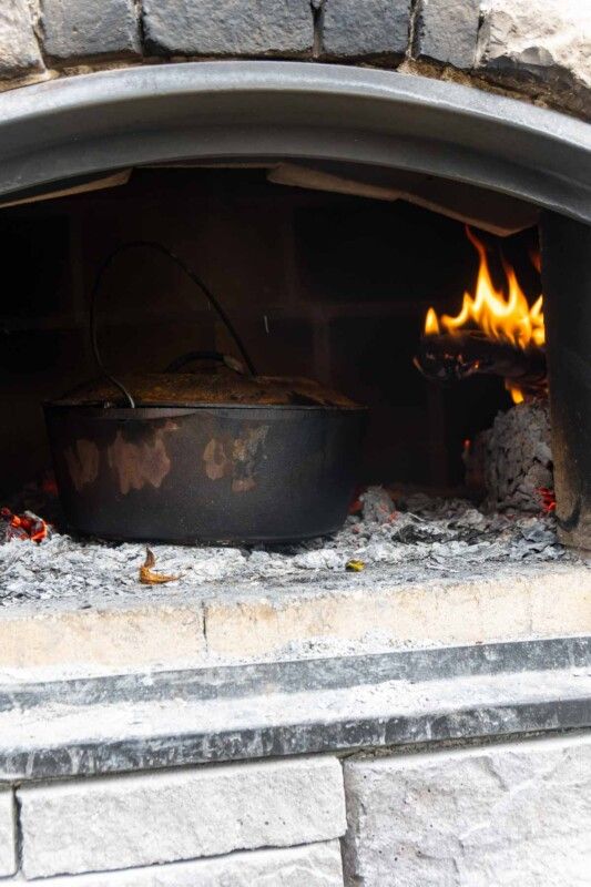 Un horno holandés en un horno de ladrillo con fuego detrás