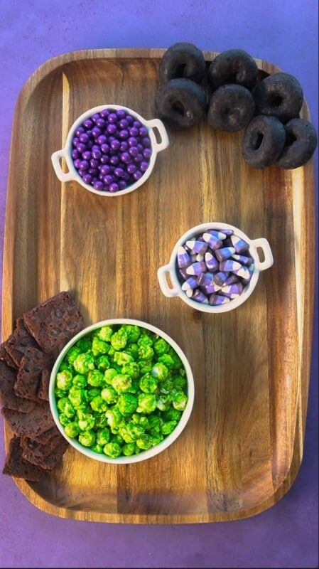 Koka dēlis ar violetām konfektēm un melniem virtuļiem