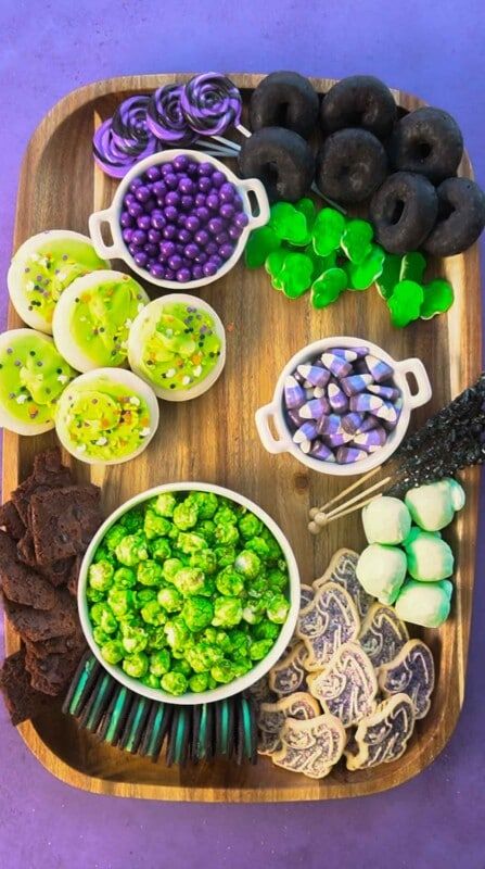 Houten bord met veel paarse en groene snacks