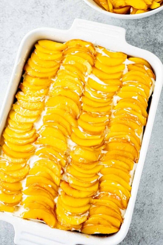 Persiku kūka ar svaigiem persikiem baltā taisnstūra traukā