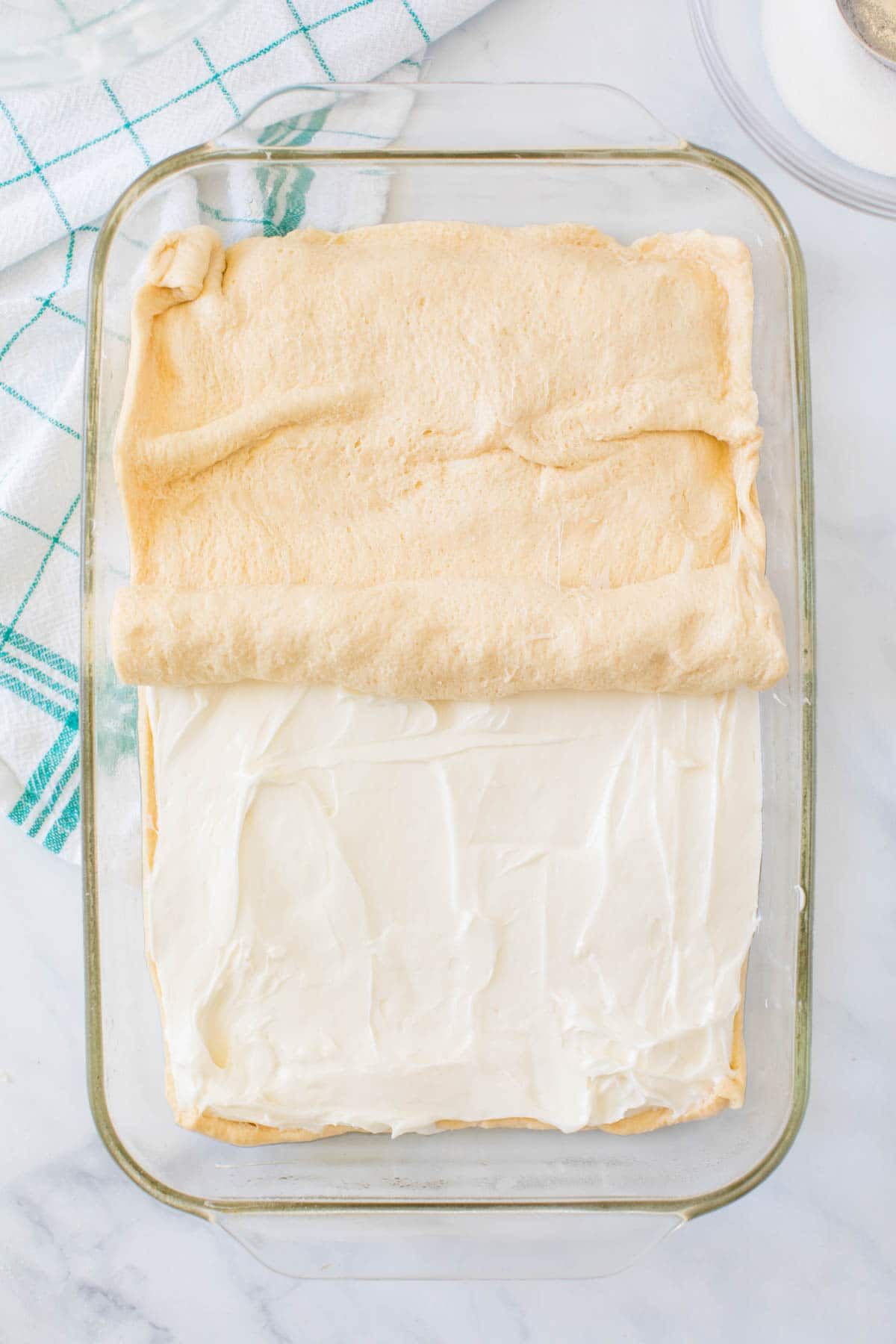 Rouleau de croissant posé sur le dessus du fromage à la crème dans un plat allant au four