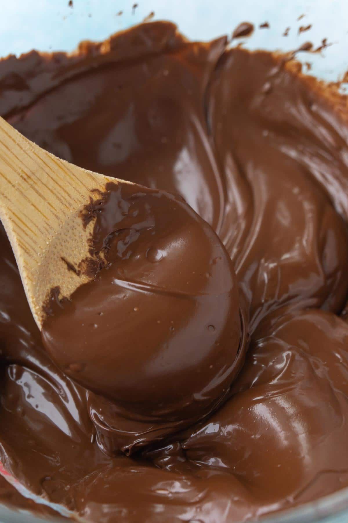 पिघल चॉकलेट के एक कटोरे में लकड़ी के चम्मच