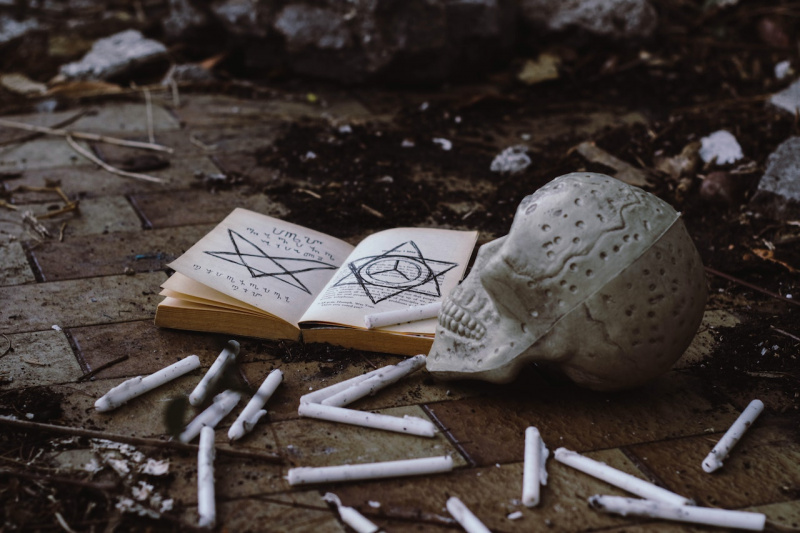   Llibre obert d'una bruixa prop d'una calavera i espelmes