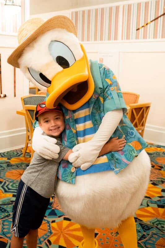 Menino abraçando o Pato Donald com uma roupa azul